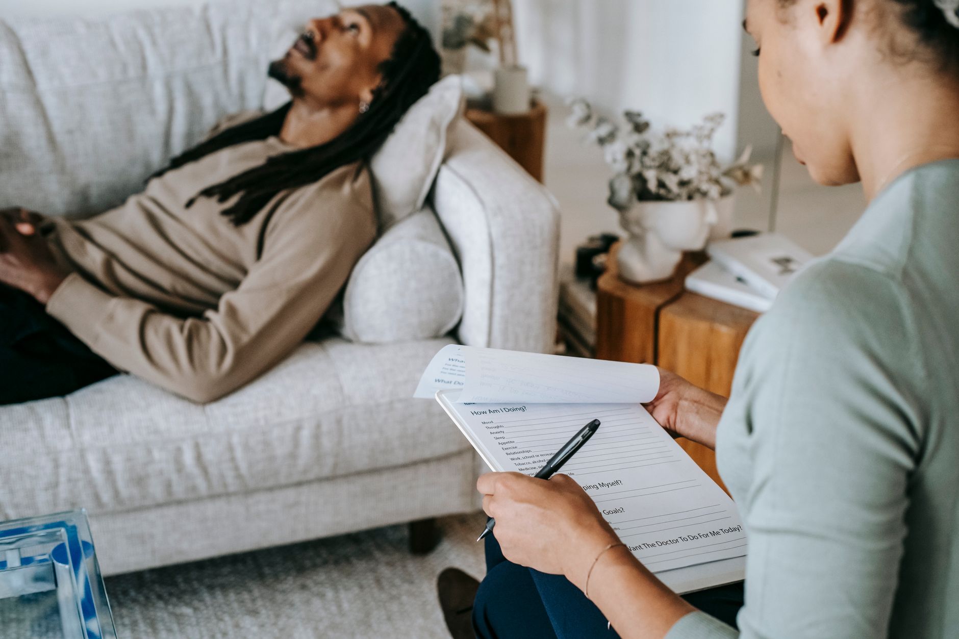 Crop anonymous African American female with paper form talking to male partner during psychotherapy in living room — UPI Study