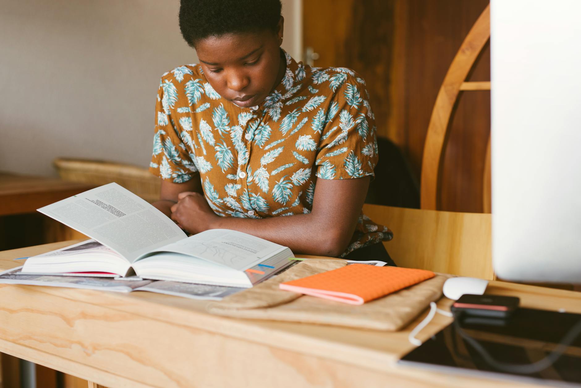 A young woman studies a book at her desk in a warm, indoor setting, illustrating a calm study environment — UPI Study