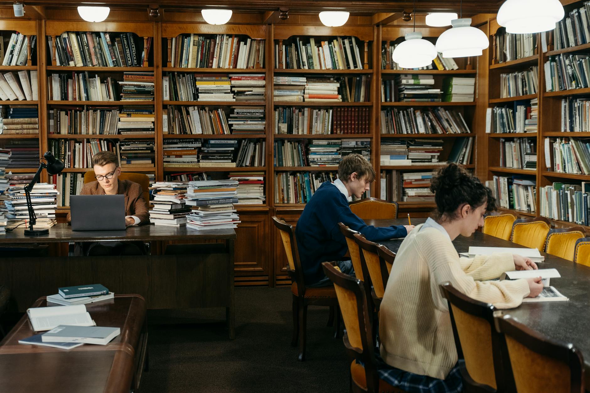 People reading and studying in a cozy library with classic bookshelves and warm lighting — UPI Study