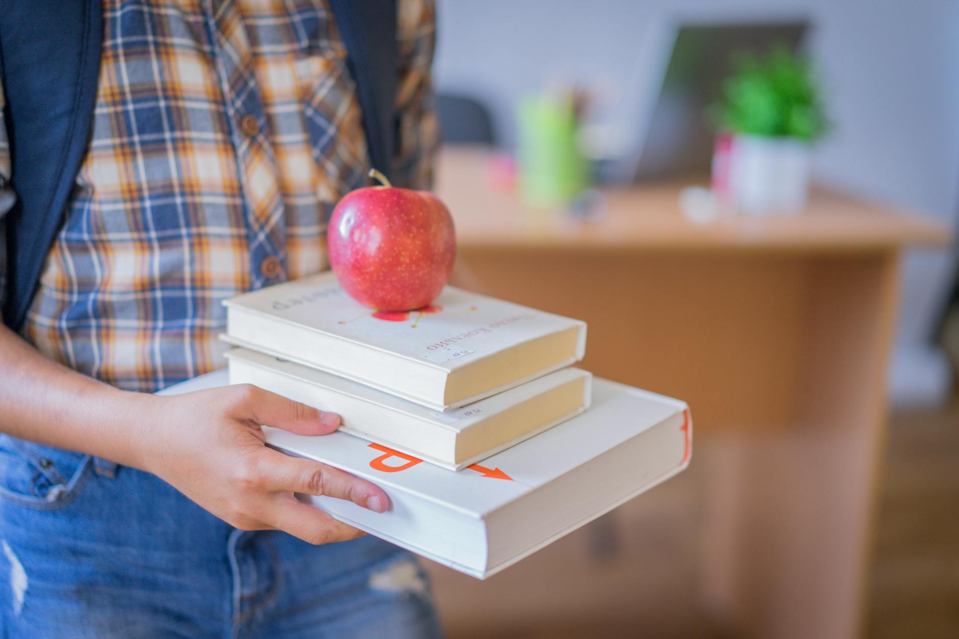 Child holding books with an apple in a classroom, symbolizing education — UPI Study
