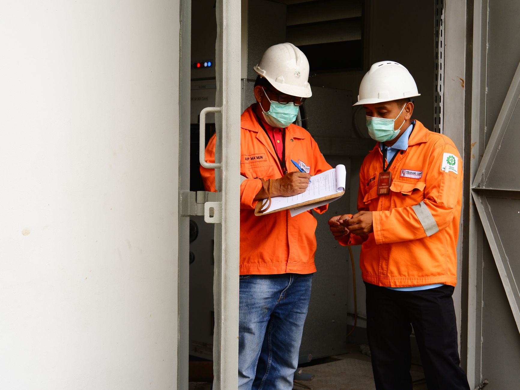 Two construction workers in safety gear discussing plans at a site entrance — UPI Study