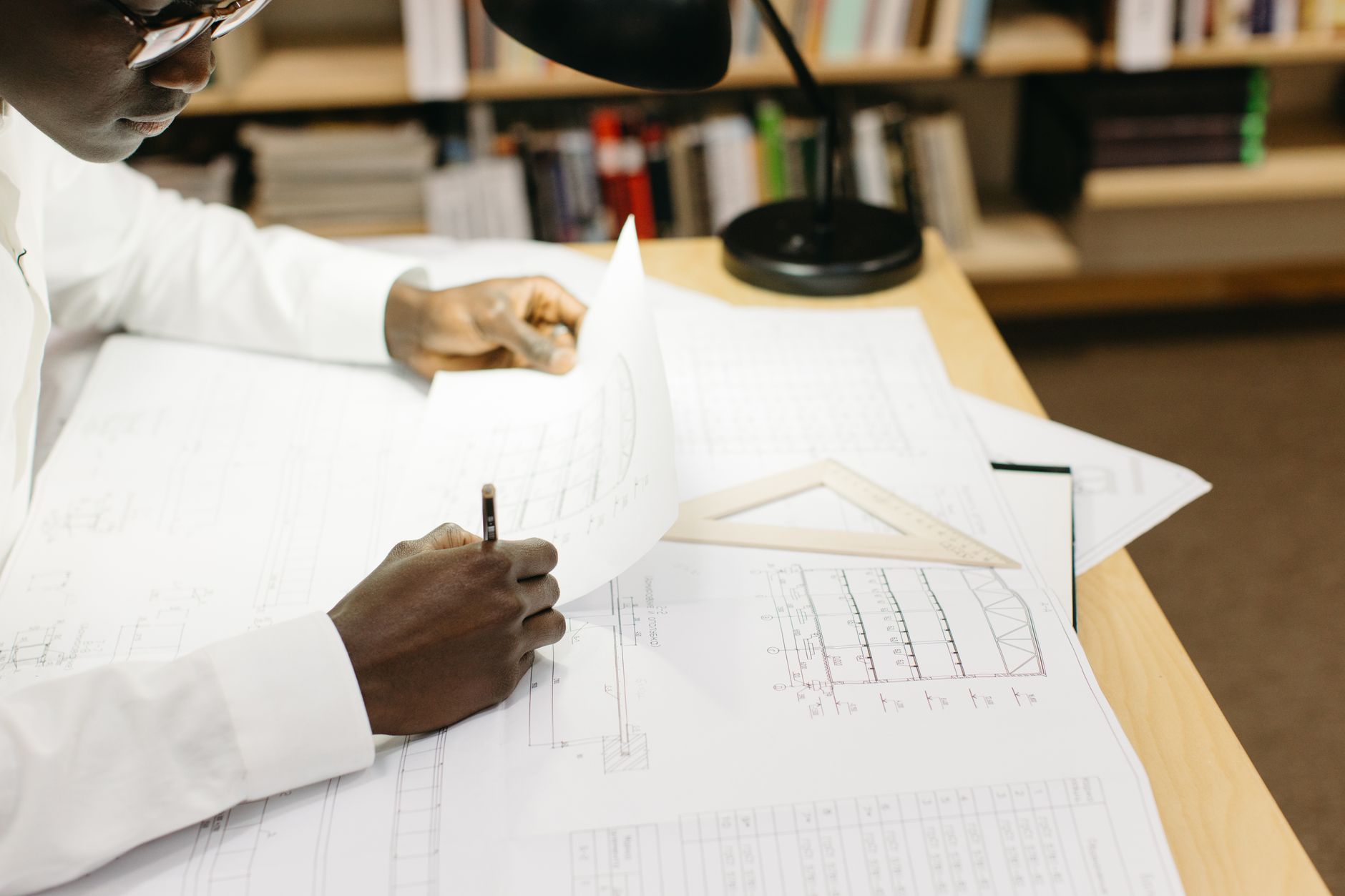 Black male architect working on blueprints at a desk in a well-lit office — UPI Study