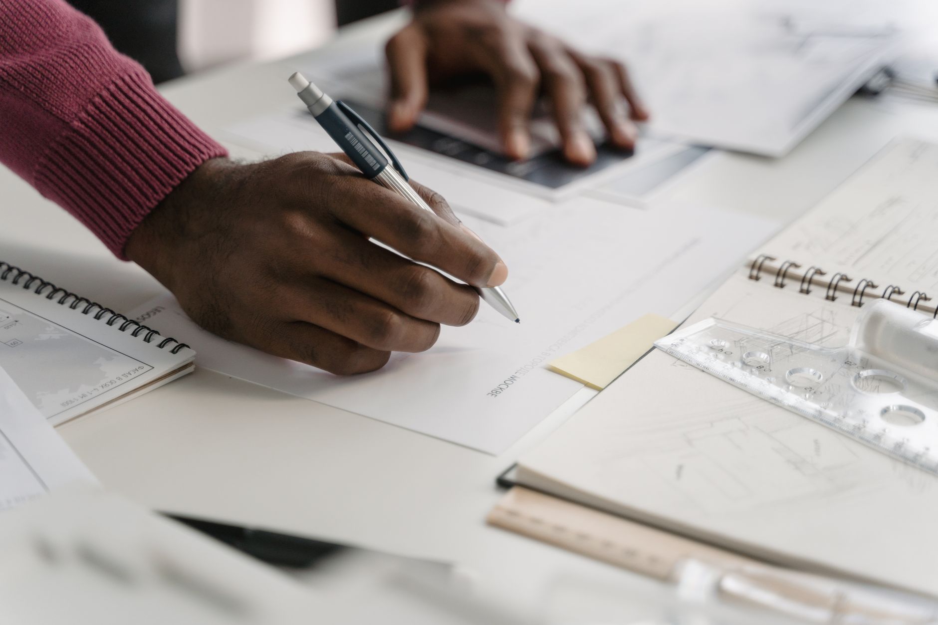 Close-up of architect drafting on blueprints in a modern office environment — UPI Study