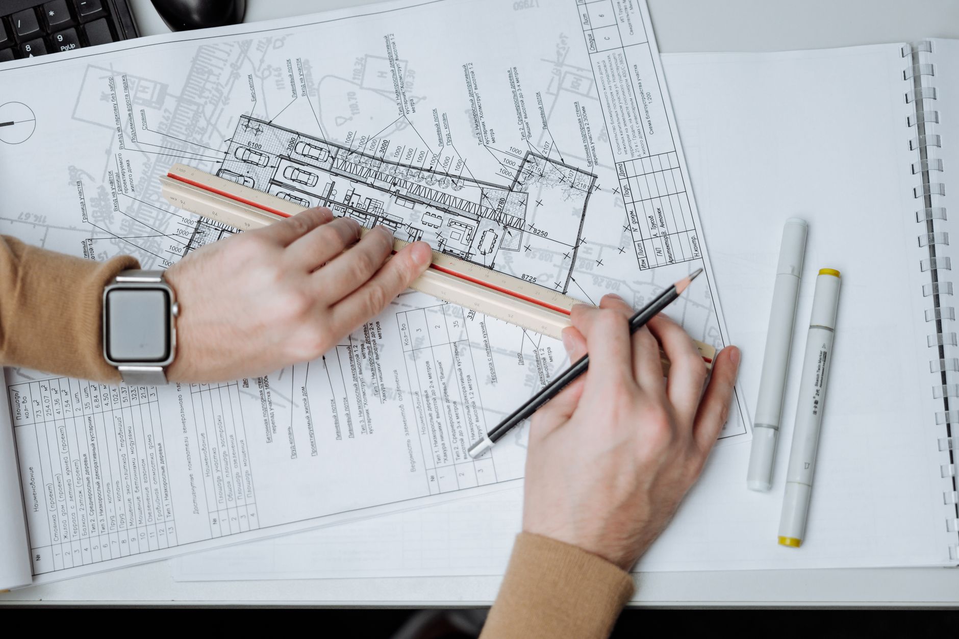 An architect uses a ruler and pencil on blueprints, showcasing workspace and planning — UPI Study