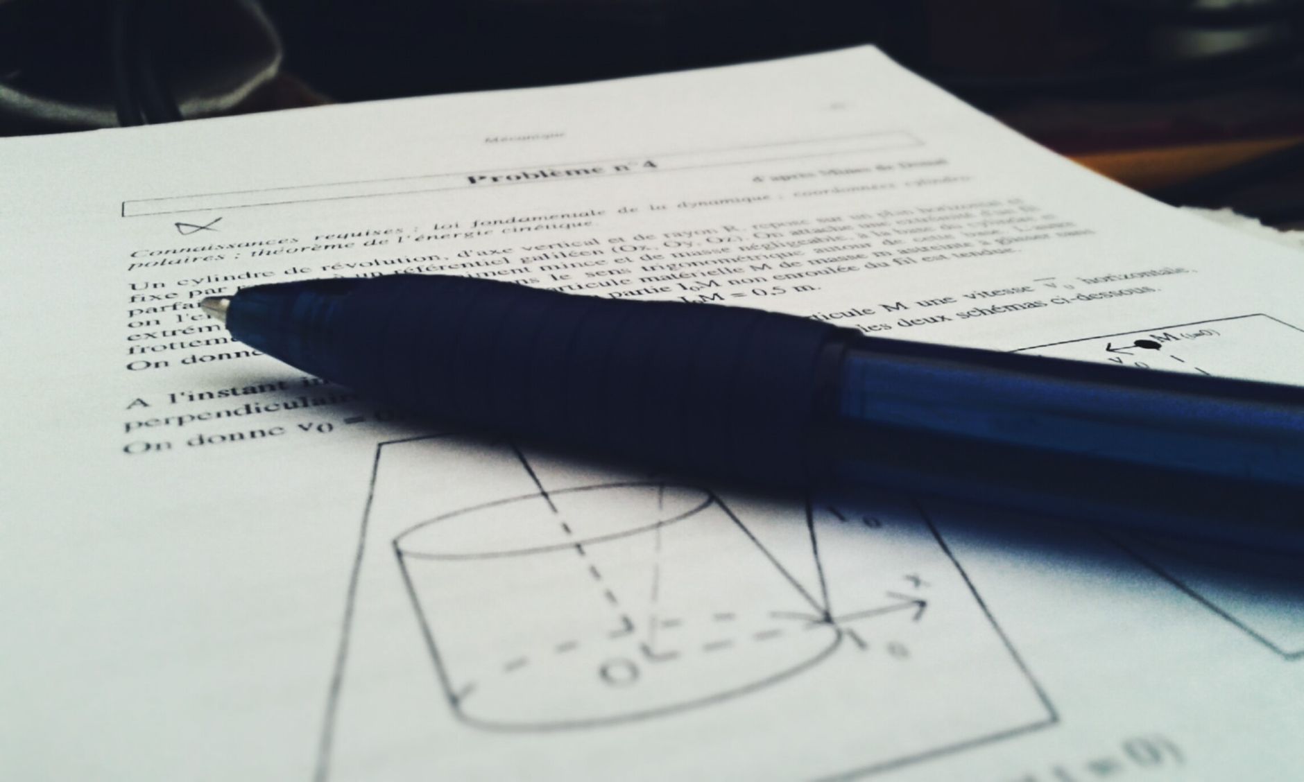 Close-up shot of a physics document with a blue pen on top, focused on equations — UPI Study