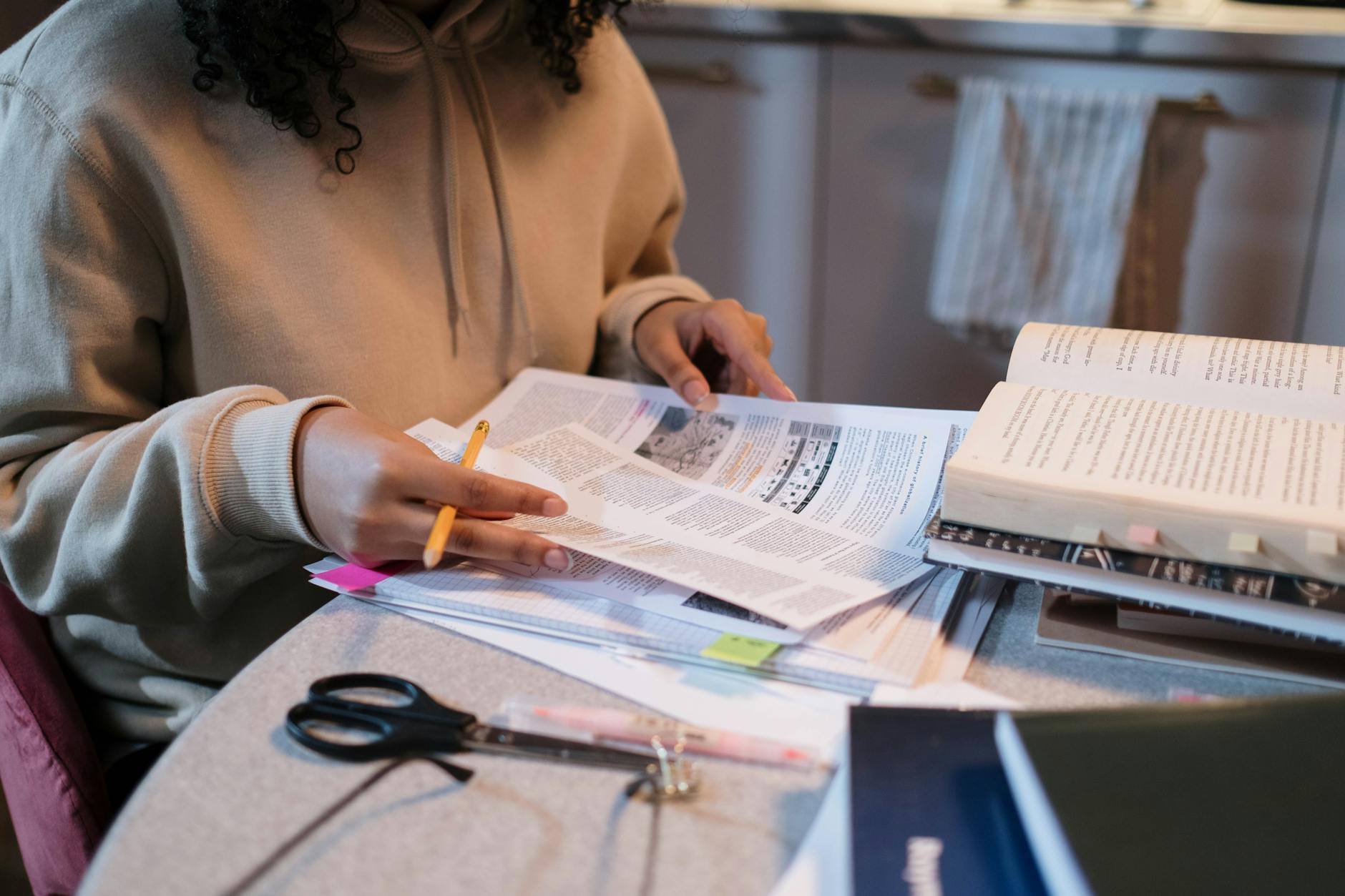 A student deeply engaged in study with books and notes spread across a table — UPI Study