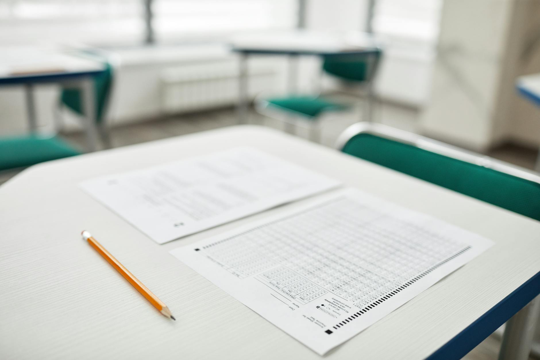 Close-up of exam papers and a pencil on a classroom desk, ready for a test — UPI Study