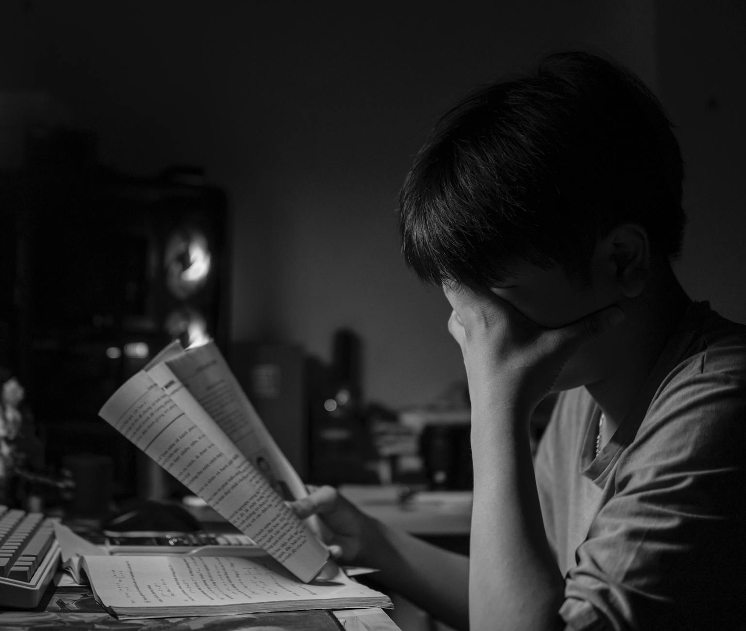 Black and white image of a young man studying at a desk, emphasizing concentration — UPI Study