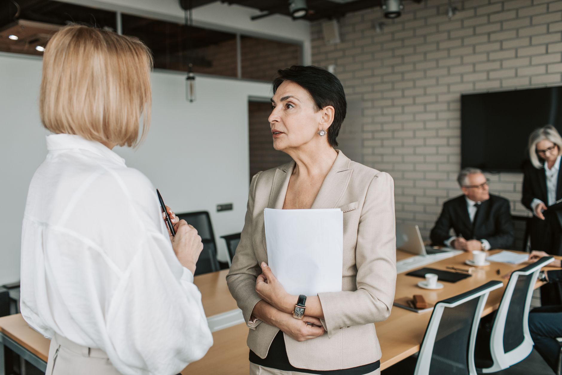 Two businesswomen engage in a conversation during a professional meeting in a modern office — UPI Study