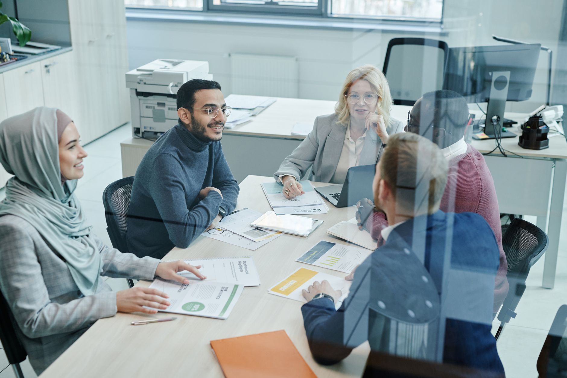 A diverse group of professionals engaged in a meeting at a modern office, promoting teamwork and collaboration — UPI Study