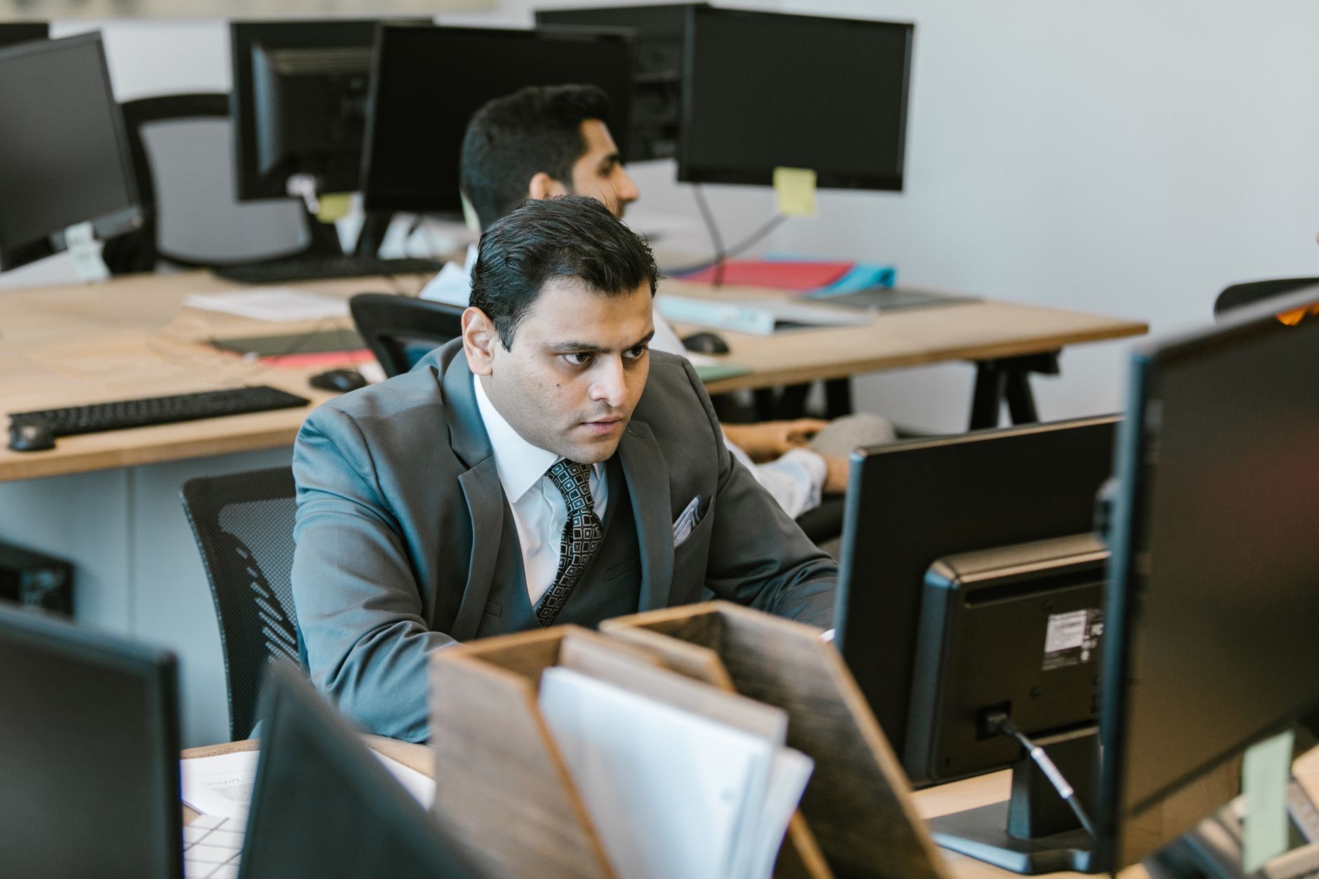 A dedicated businessman in a suit concentrating on work at a modern office desk — UPI Study
