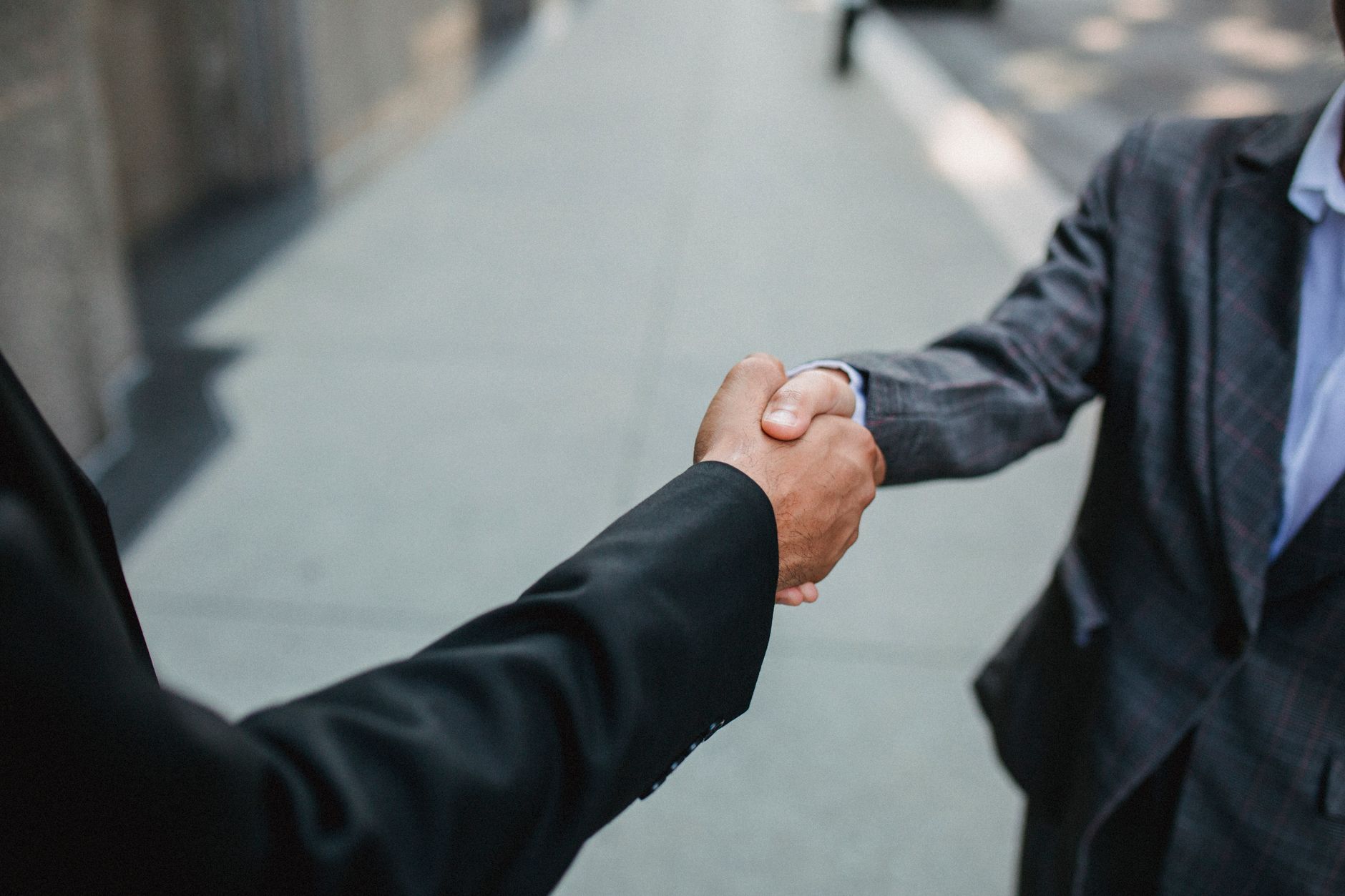 Close-up of two businessmen shaking hands outside, symbolizing partnership and agreement — UPI Study