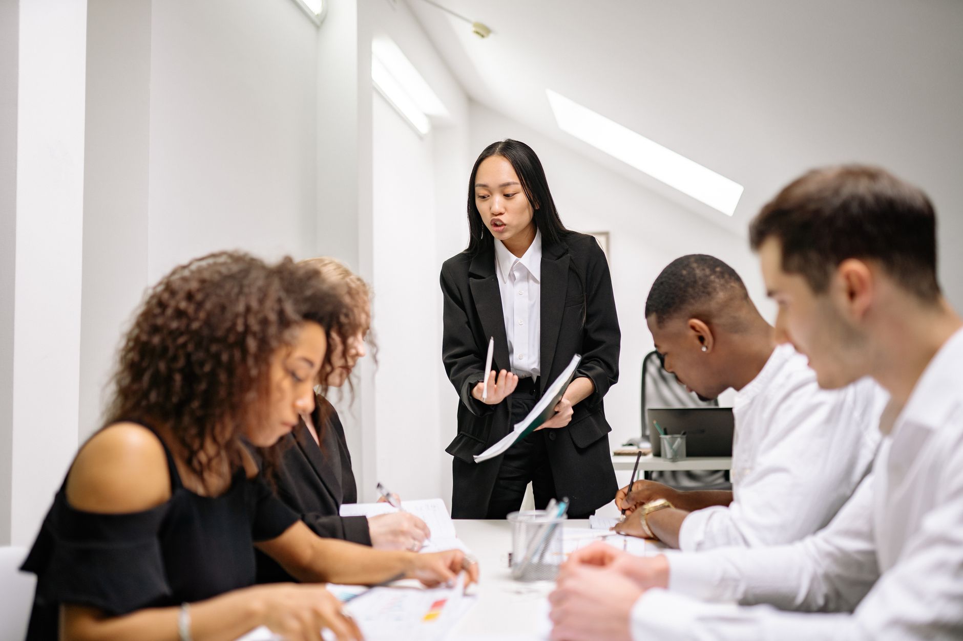 A diverse group of business people collaborating in an office meeting, led by a woman — UPI Study