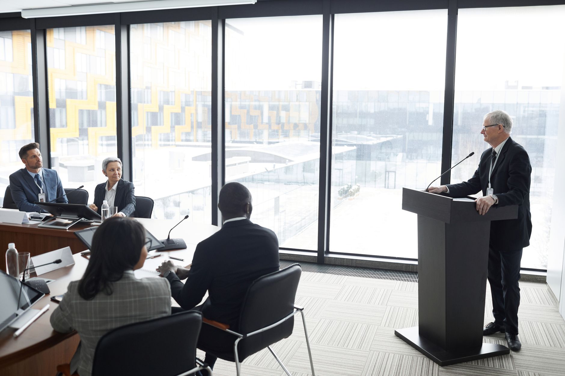 Corporate professionals engaged in a formal business meeting in a modern conference room setting — UPI Study