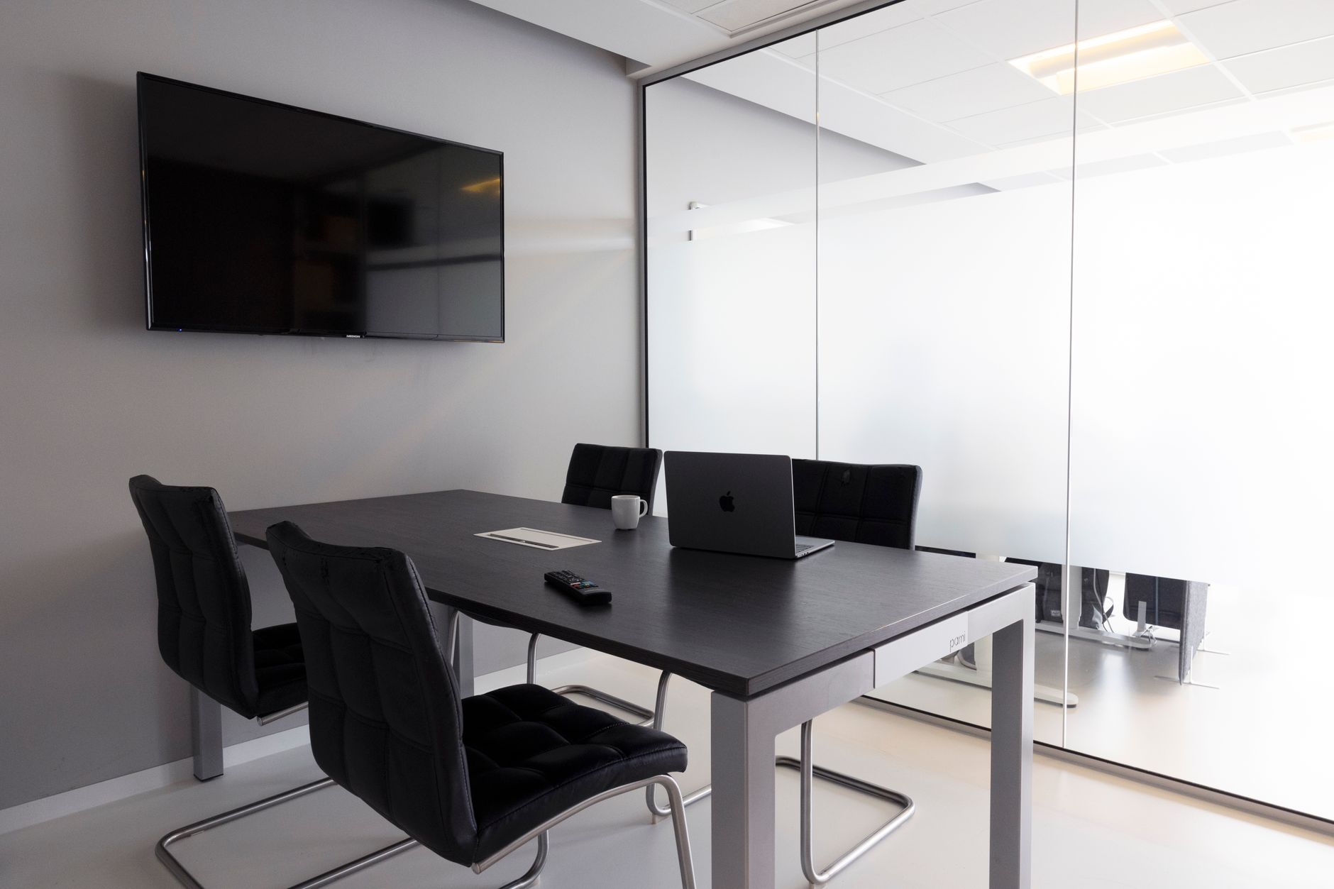 Contemporary meeting room with glass walls, laptop, and television for business discussions — UPI Study