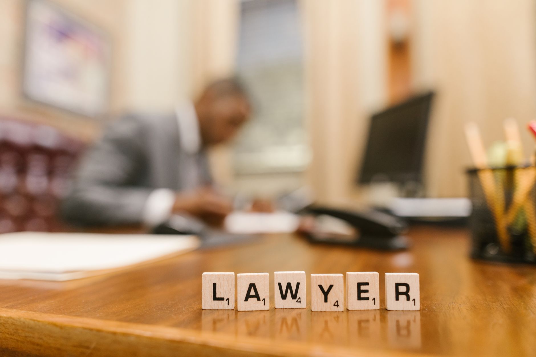 Wooden letter tiles spelling 'LAWYER' on a desk, with blurred office setting in the background — UPI Study