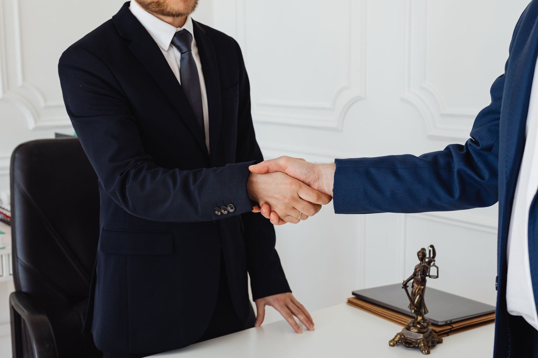 Two men in suits shaking hands in a formal office environment symbolizing an agreement — UPI Study