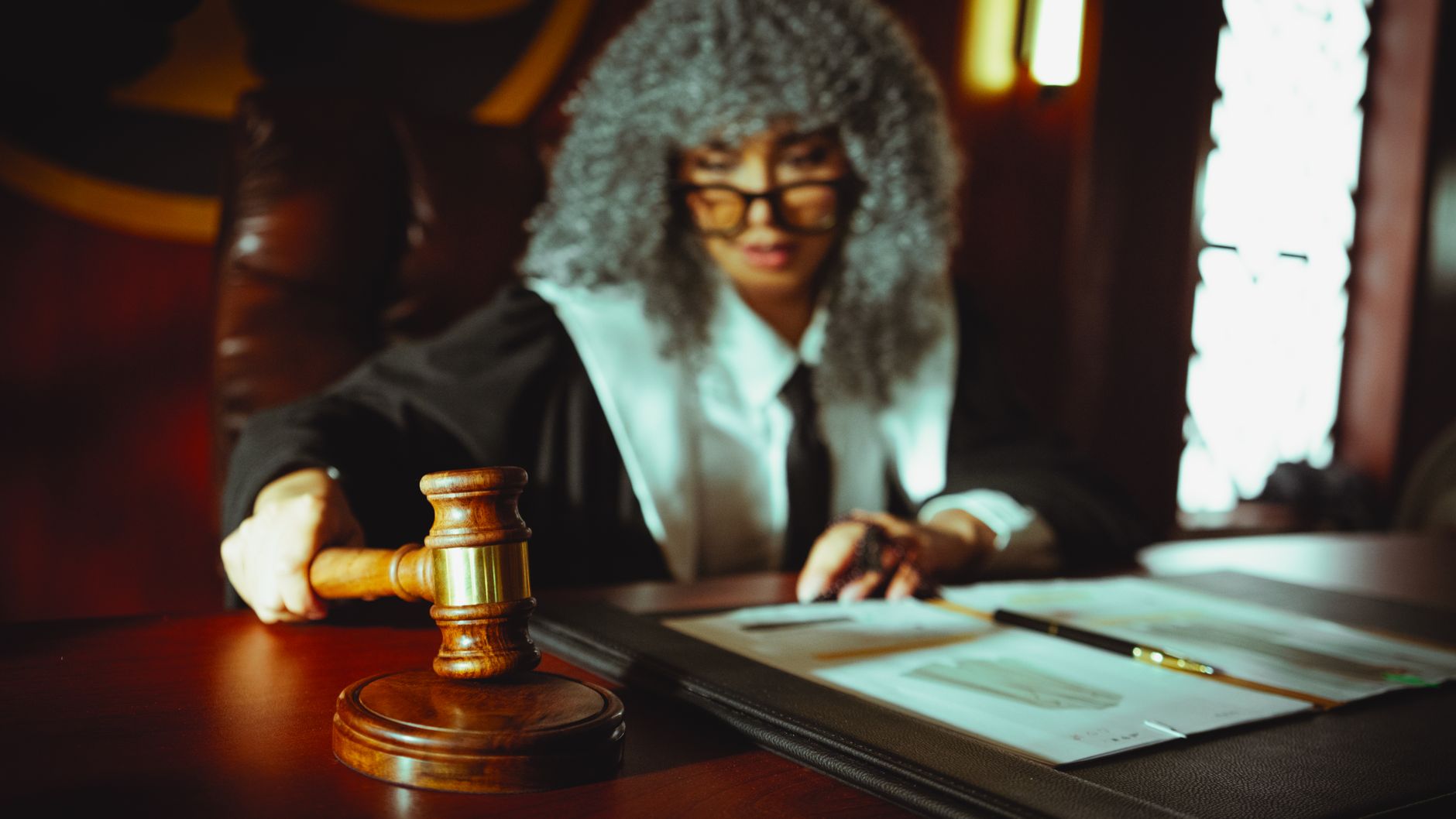 Female judge in a courtroom setting, focusing on legal documents with a gavel — UPI Study