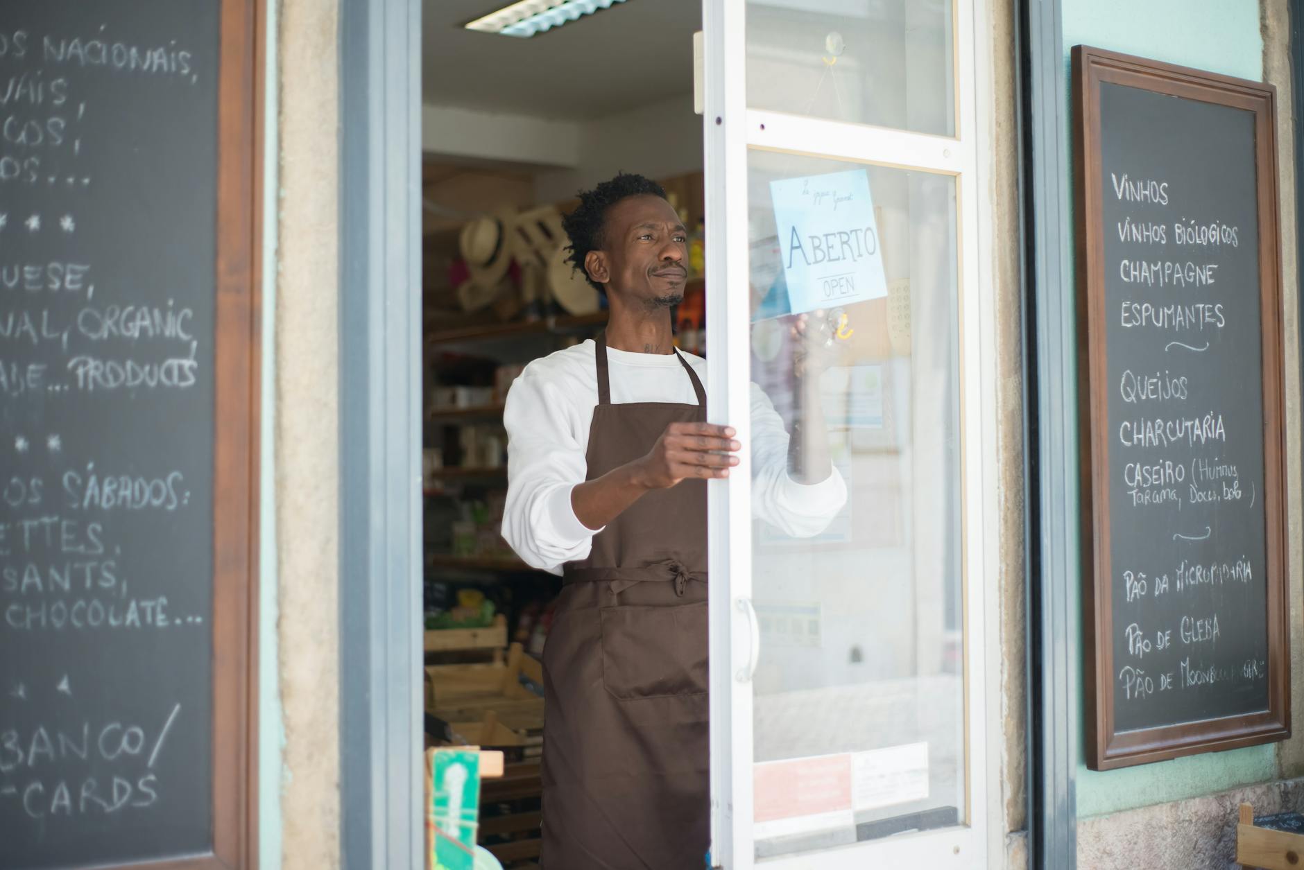 A man in an apron opens a grocery store door in Portugal, ready for business — UPI Study