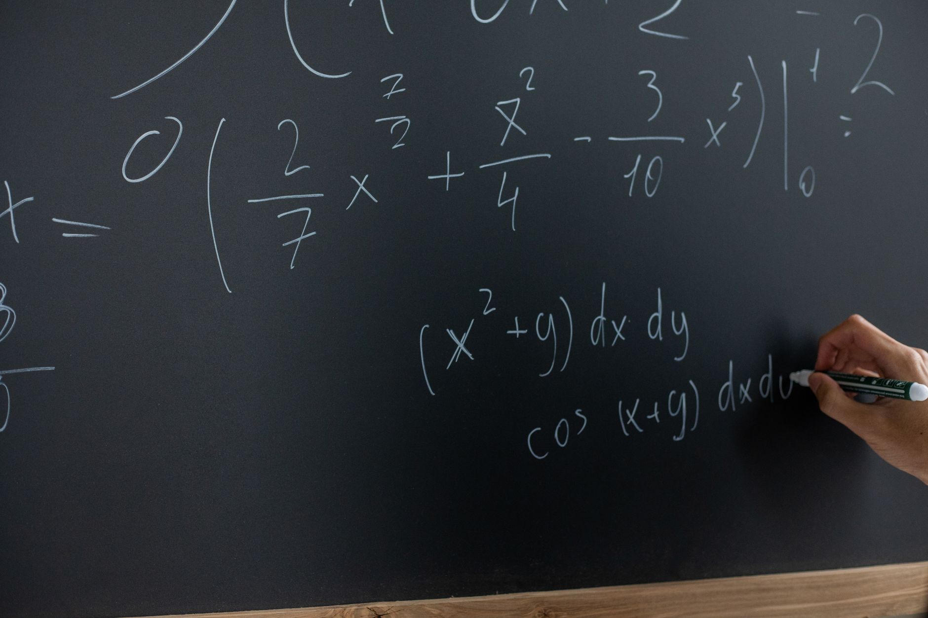 Hand writing mathematical equations on a chalkboard in a classroom setting — UPI Study