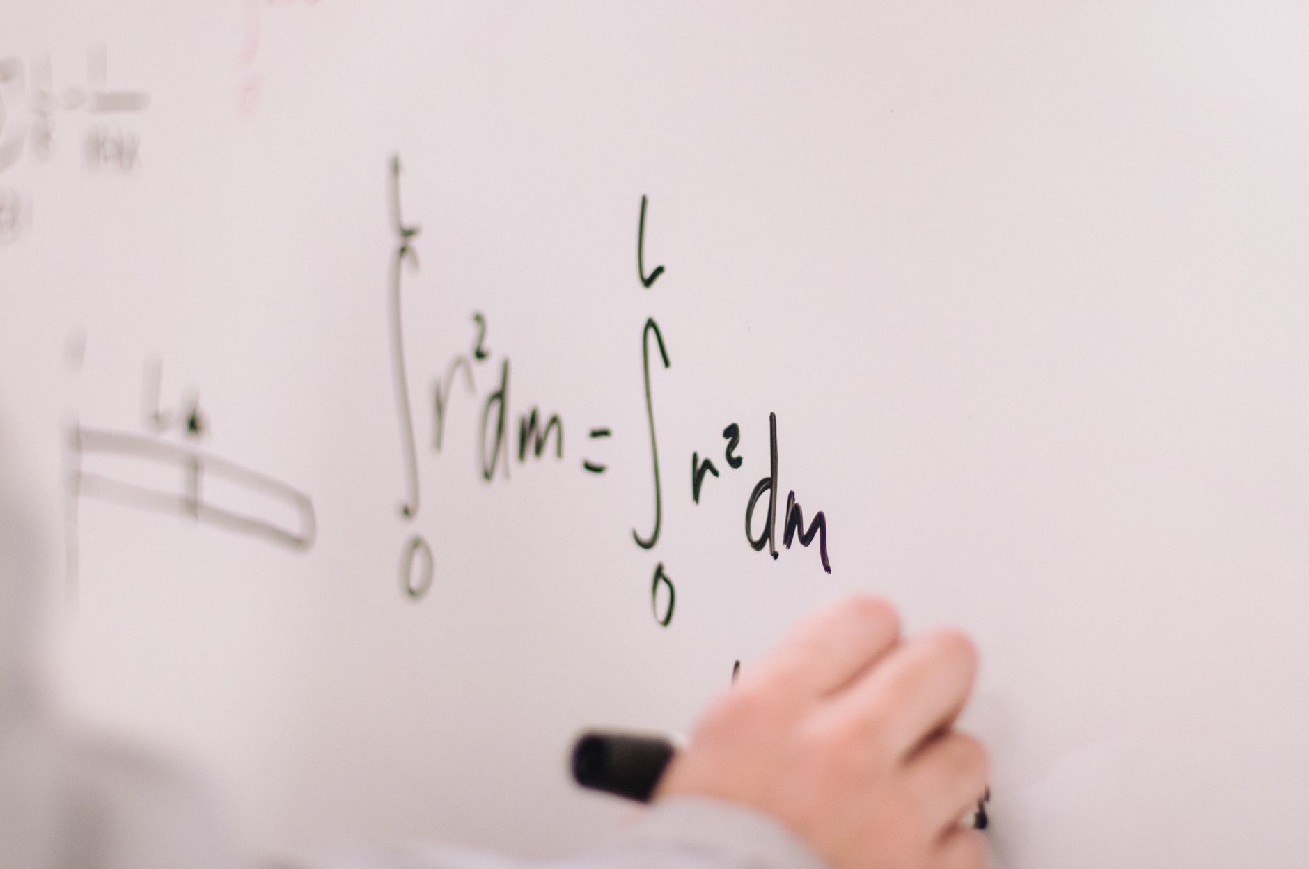 Person writing math equations on a whiteboard, focusing on integrals and formulas — UPI Study