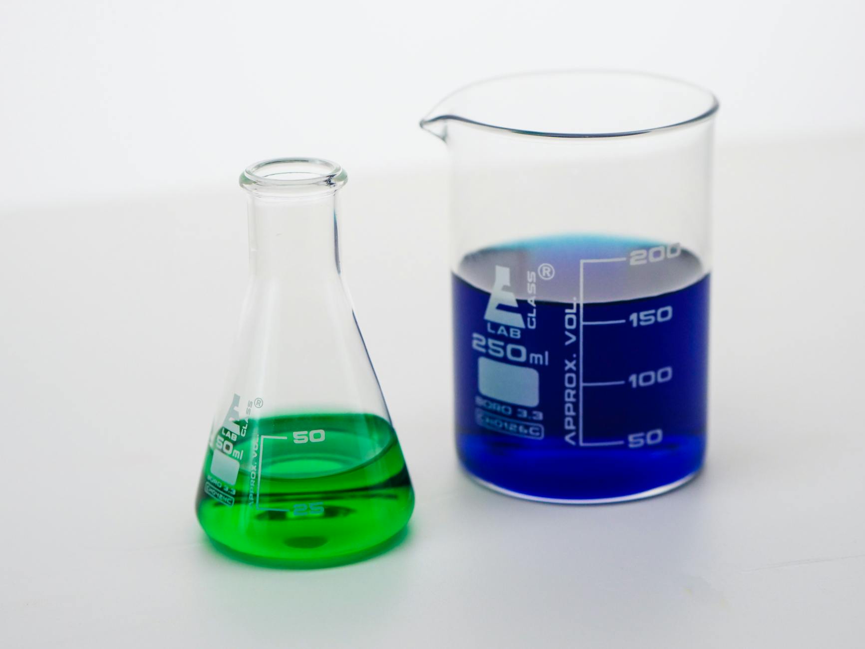 Close-up of beakers filled with vibrant green and blue liquids in a laboratory setting — UPI Study
