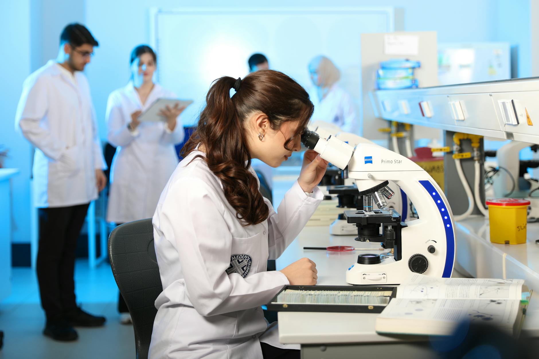 Young female scientist examining samples under a microscope in a modern laboratory setting — UPI Study