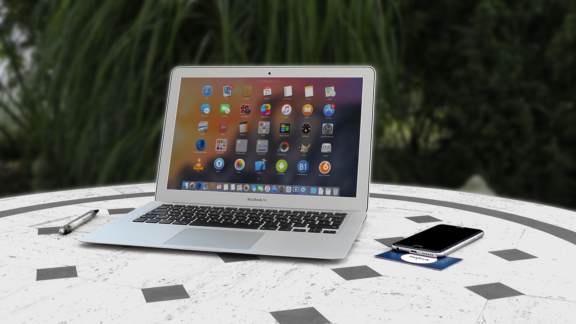 Open laptop with app icons displayed, smartphone and pen on white table outdoors — UPI Study