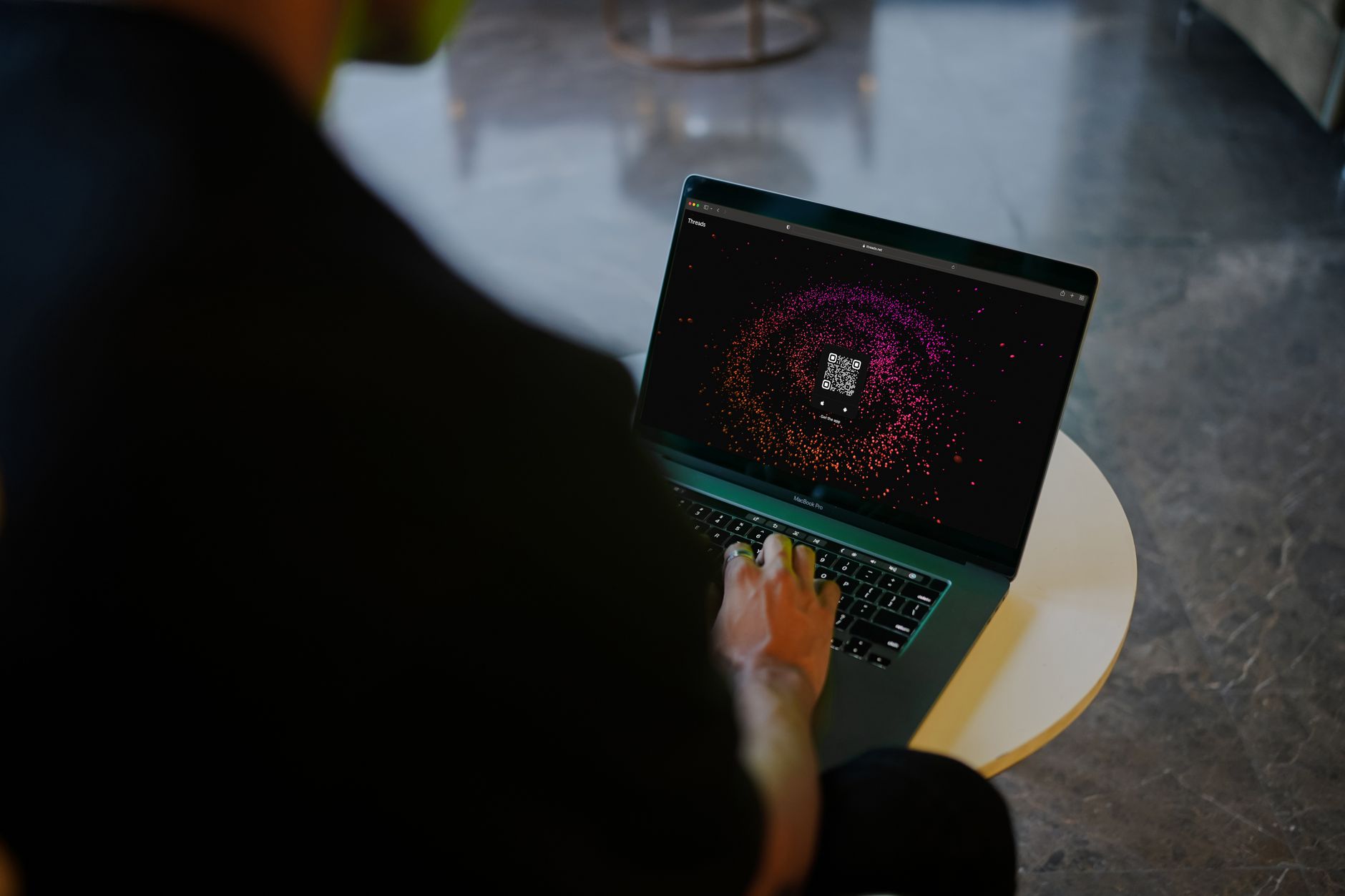 A person interacts with a colorful QR code display on a laptop in a modern indoor setting — UPI Study