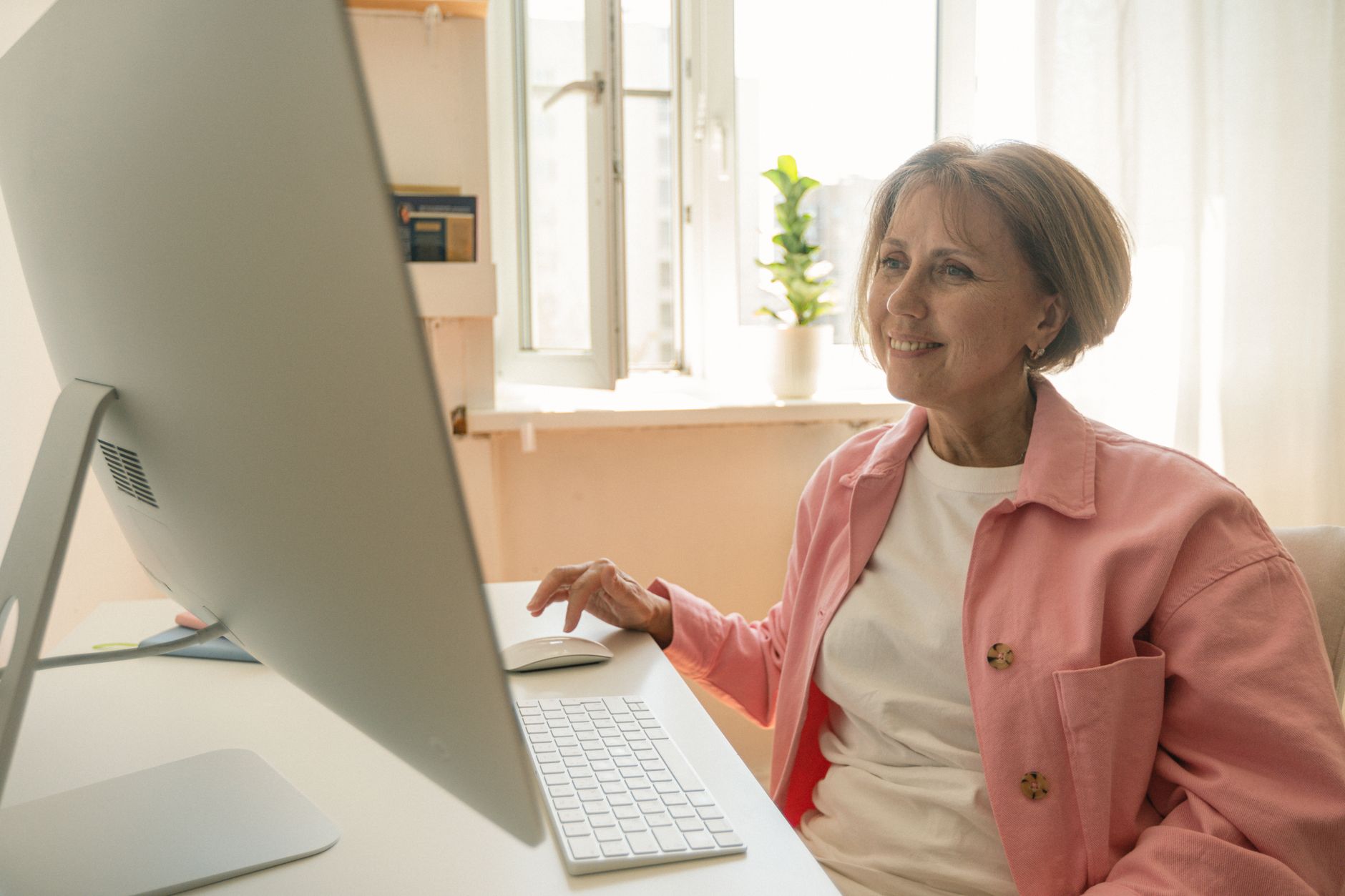 Smiling senior woman using a desktop computer at home, enjoying technology — UPI Study