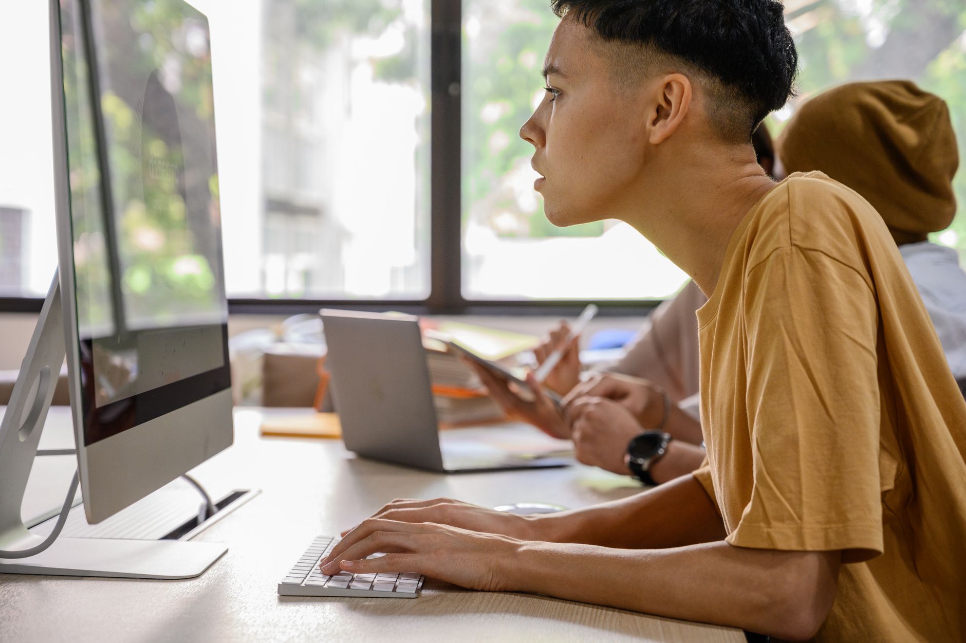 Diverse young adults engaged in work at desks with computers in a modern office — UPI Study