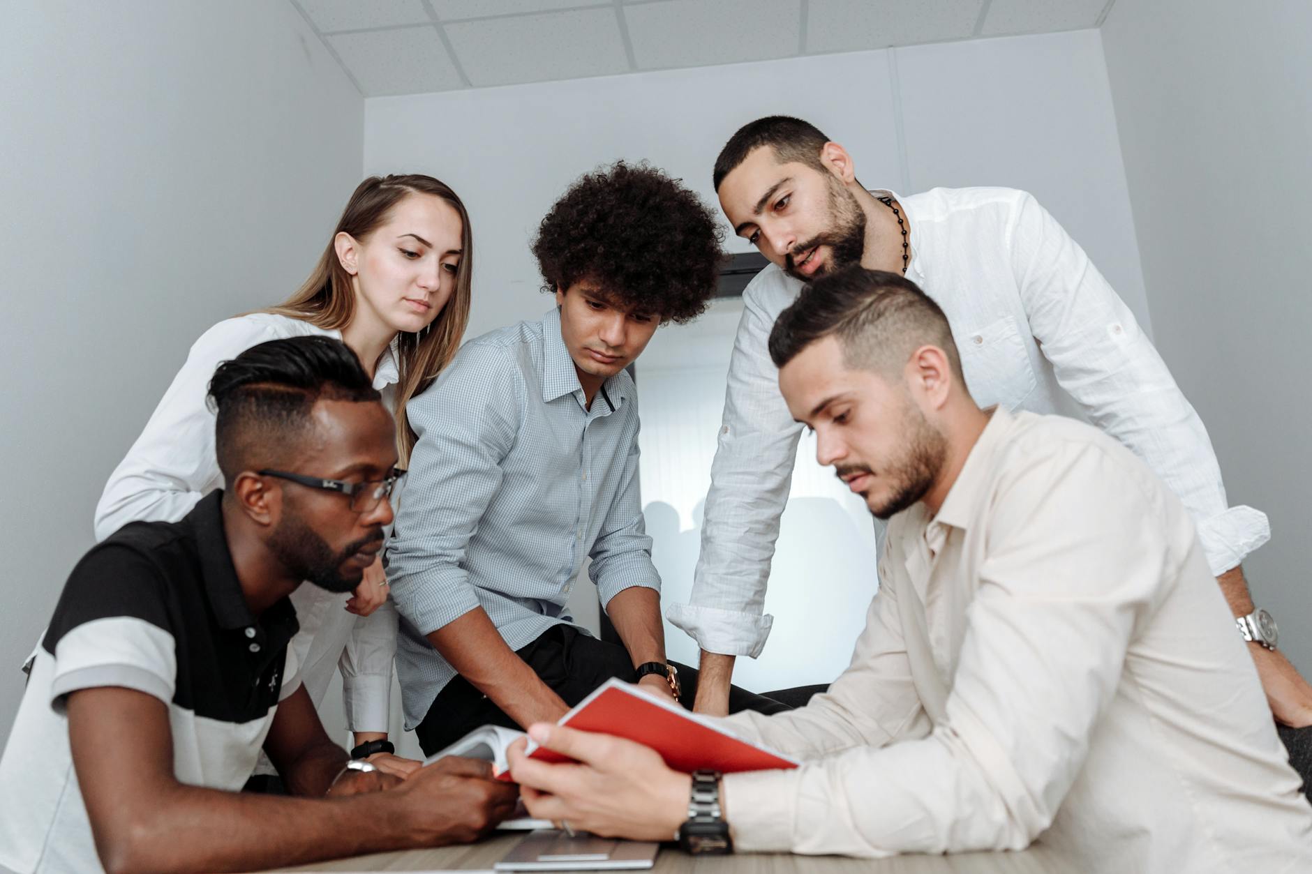 A multicultural team engaged in a collaborative office meeting, discussing ideas around a table — UPI Study
