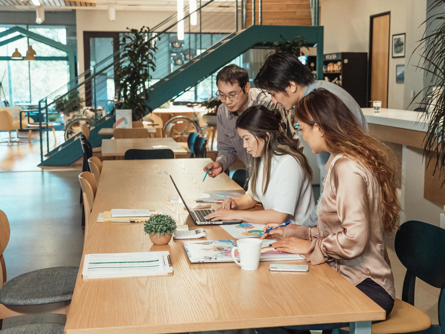 Four professionals collaborating in a modern workspace, focused on a project — UPI Study