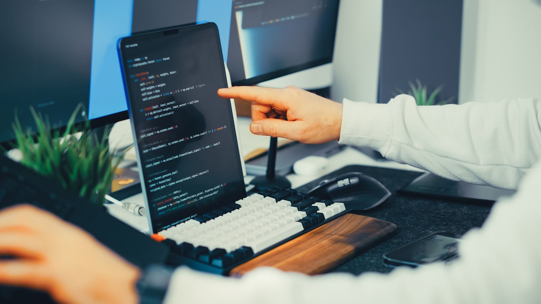 A programmer working on code with a laptop and monitor setup in an office — UPI Study