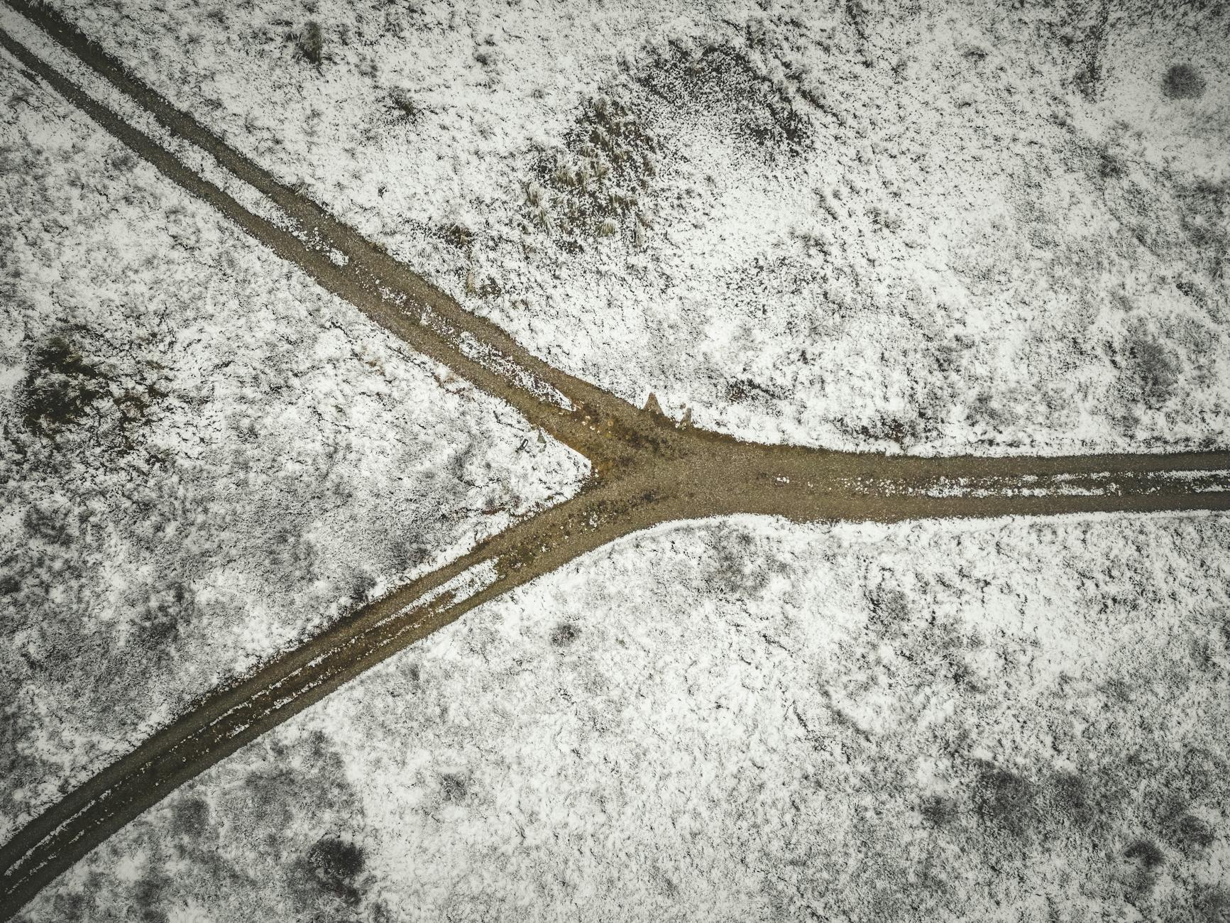 Drone shot of a snowy landscape with a forked dirt road in Bindslev, Denmark — UPI Study