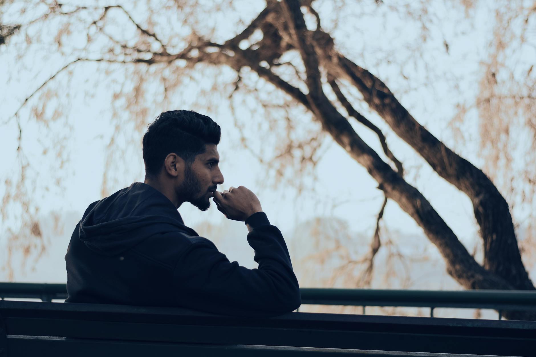 Man in deep thought sitting on a bench in a serene autumn park setting — UPI Study