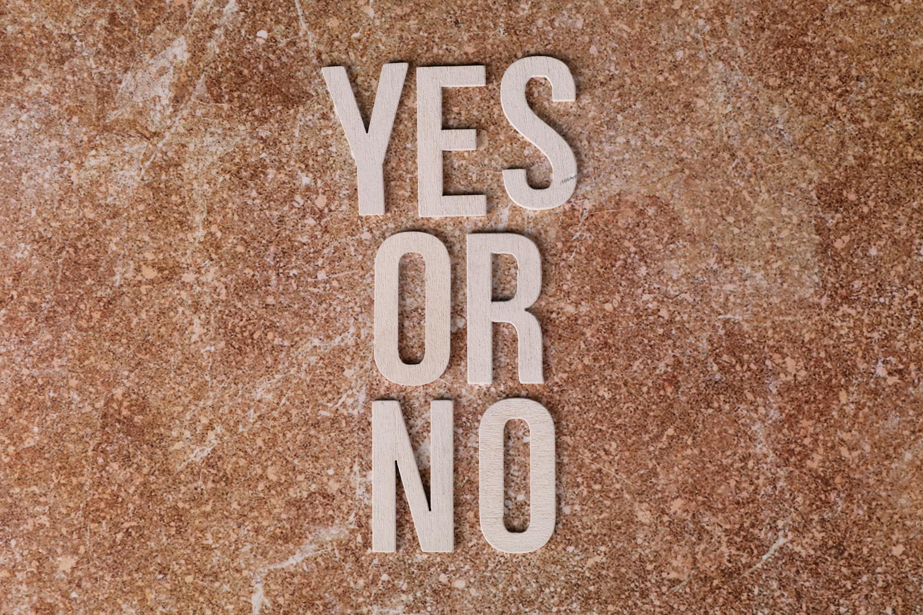 Wooden letters on marble background spell 'YES OR NO' symbolizing choices — UPI Study