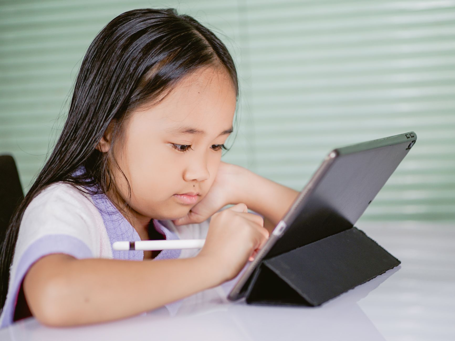 A young girl using a tablet for online learning, focused and engaged with her digital pen — UPI Study