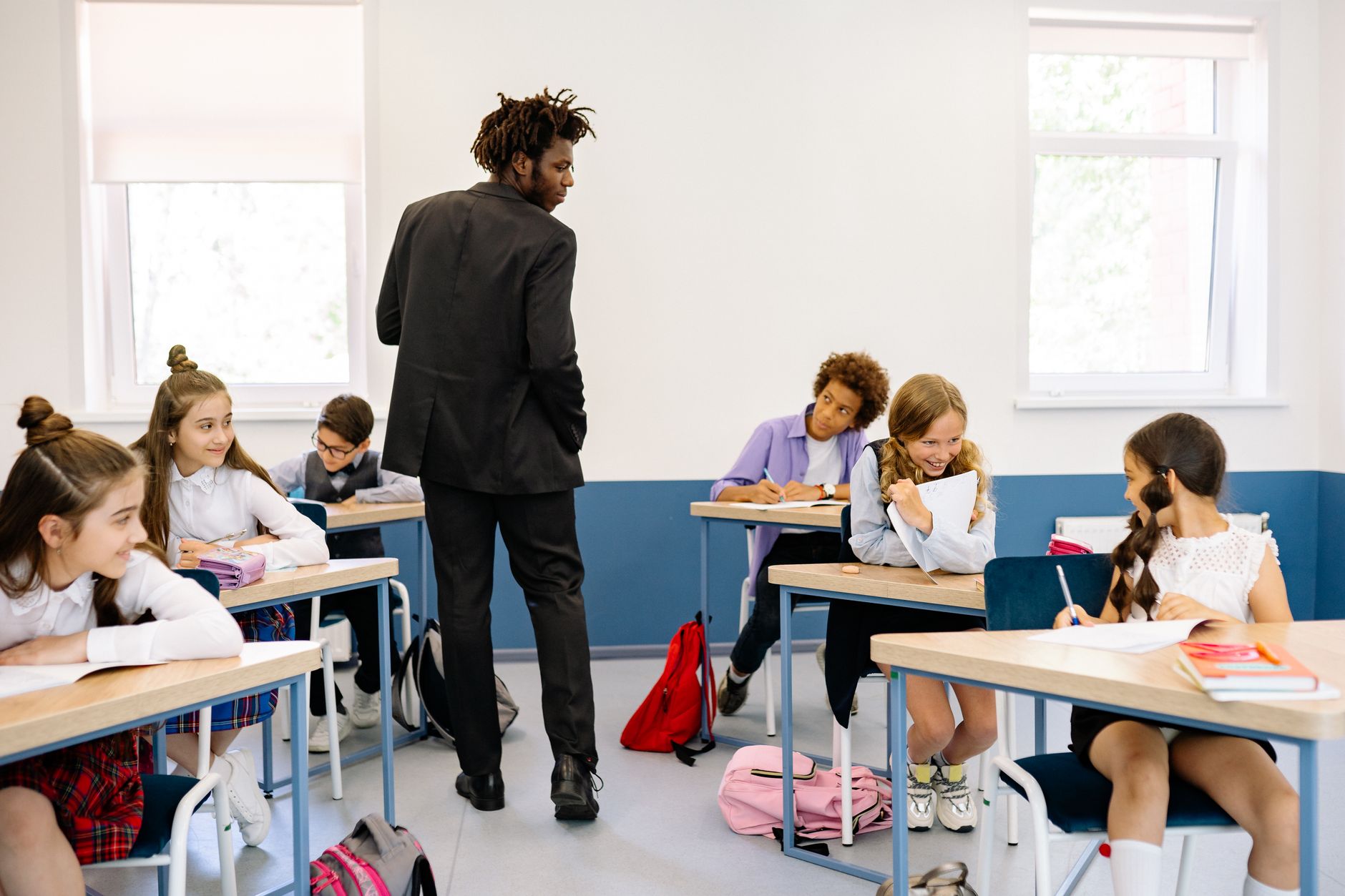 A teacher watches over students who are engaged in classroom activities on a bright day — UPI Study