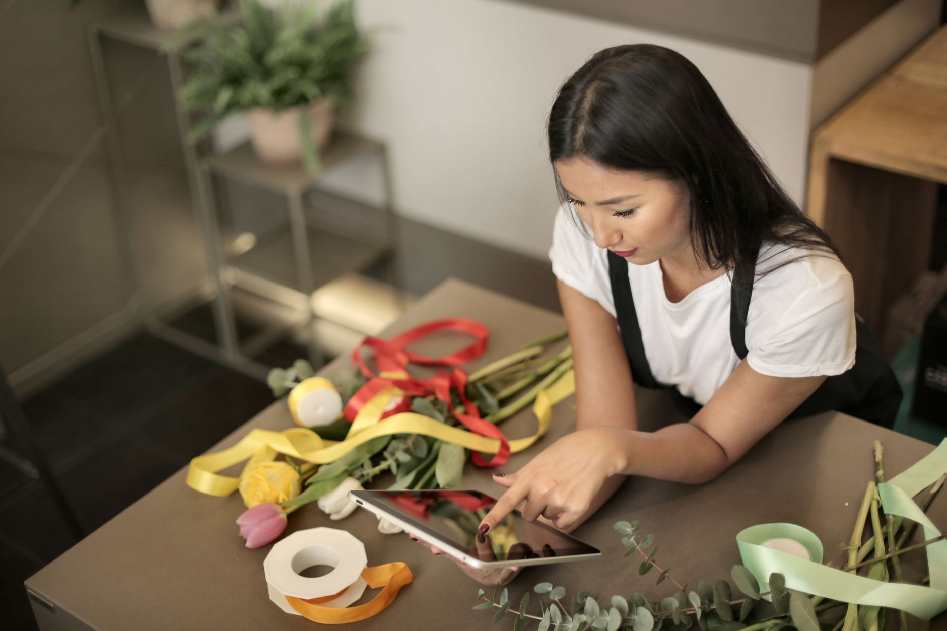 Florist using a tablet while arranging a colorful bouquet in a shop indoors — UPI Study