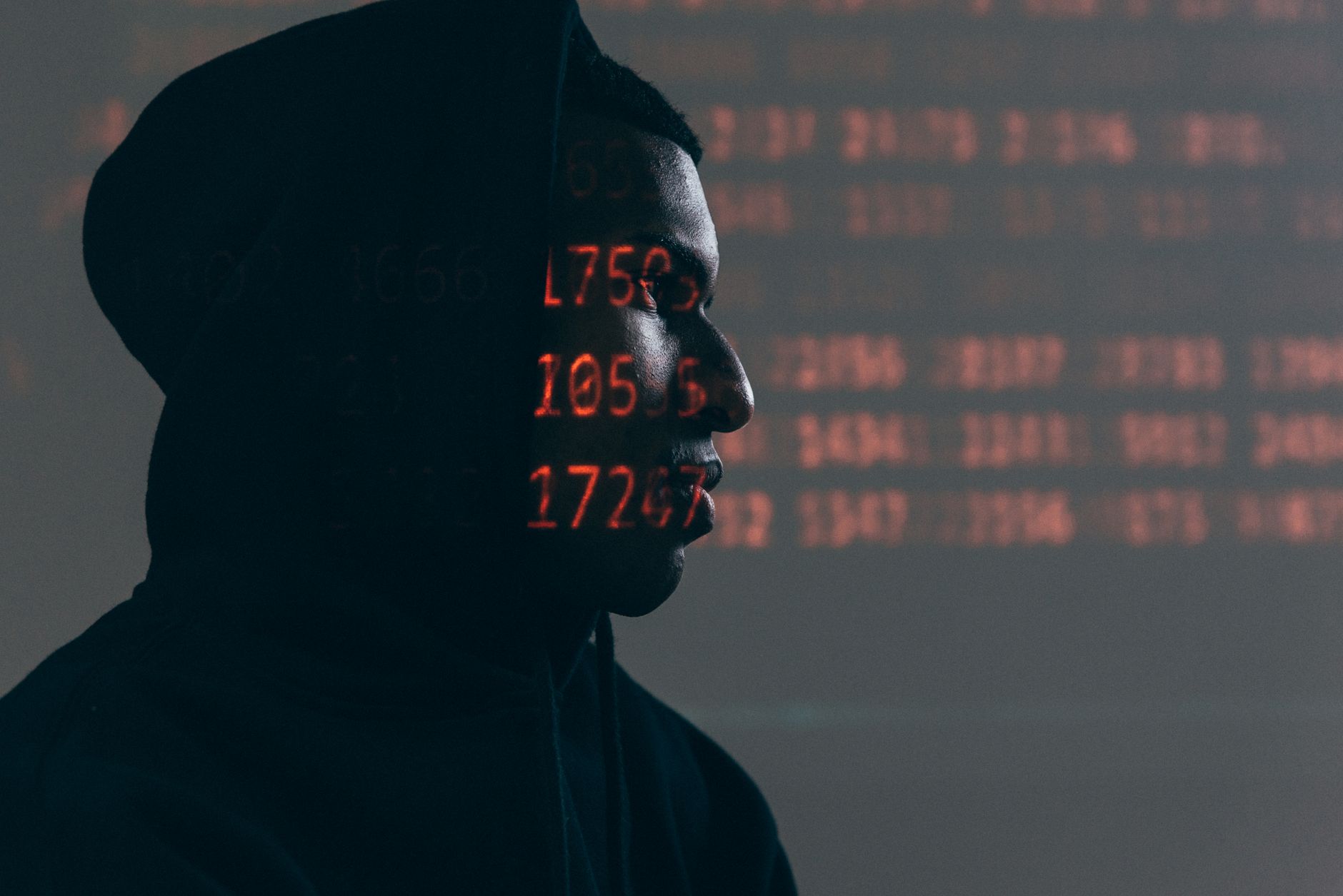 Side profile of a man in a hoodie, surrounded by red code, depicting cybersecurity theme — UPI Study