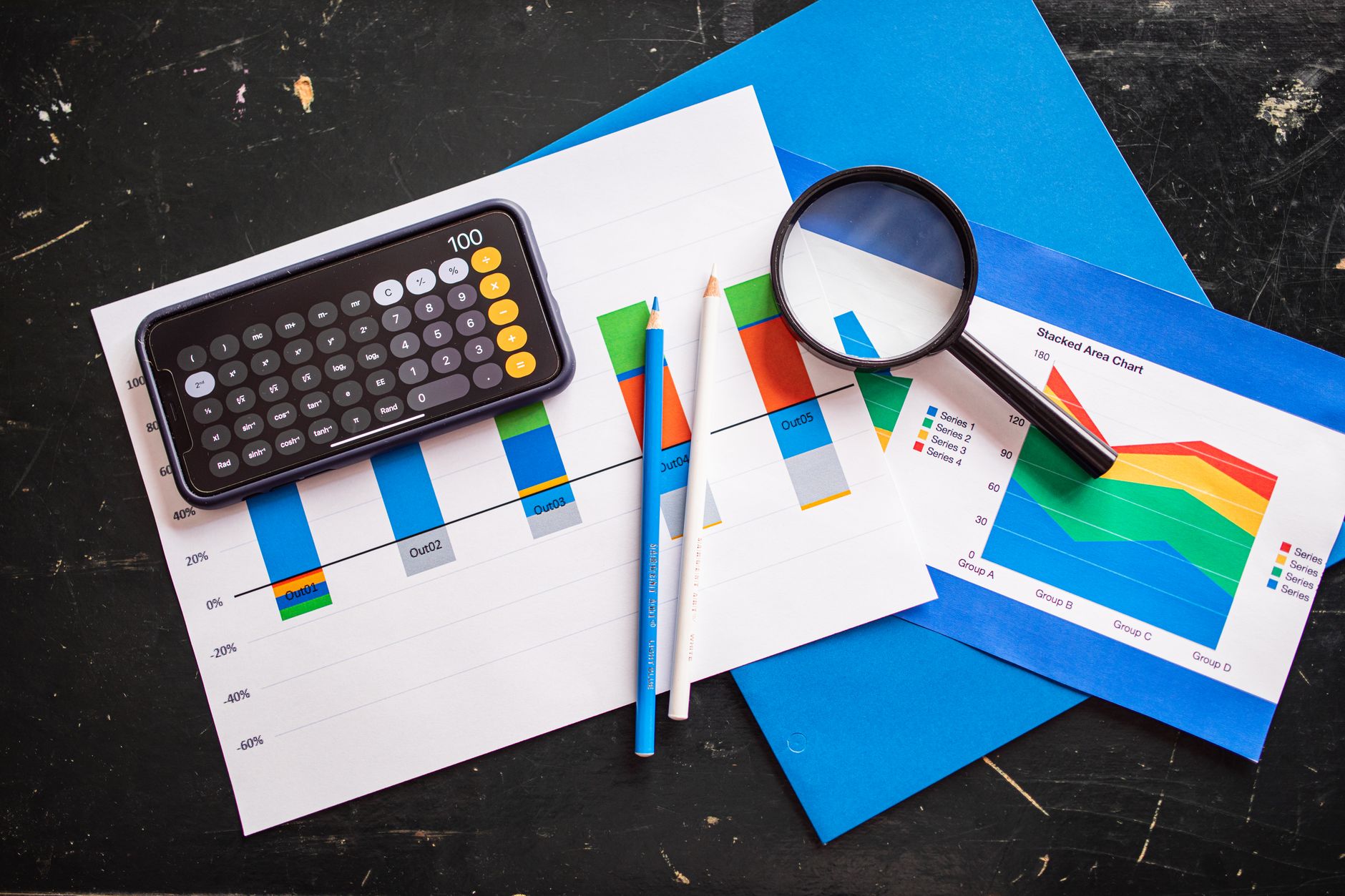 Top view of financial charts with a smartphone calculator, magnifying glass, and pencils on a desk — UPI Study
