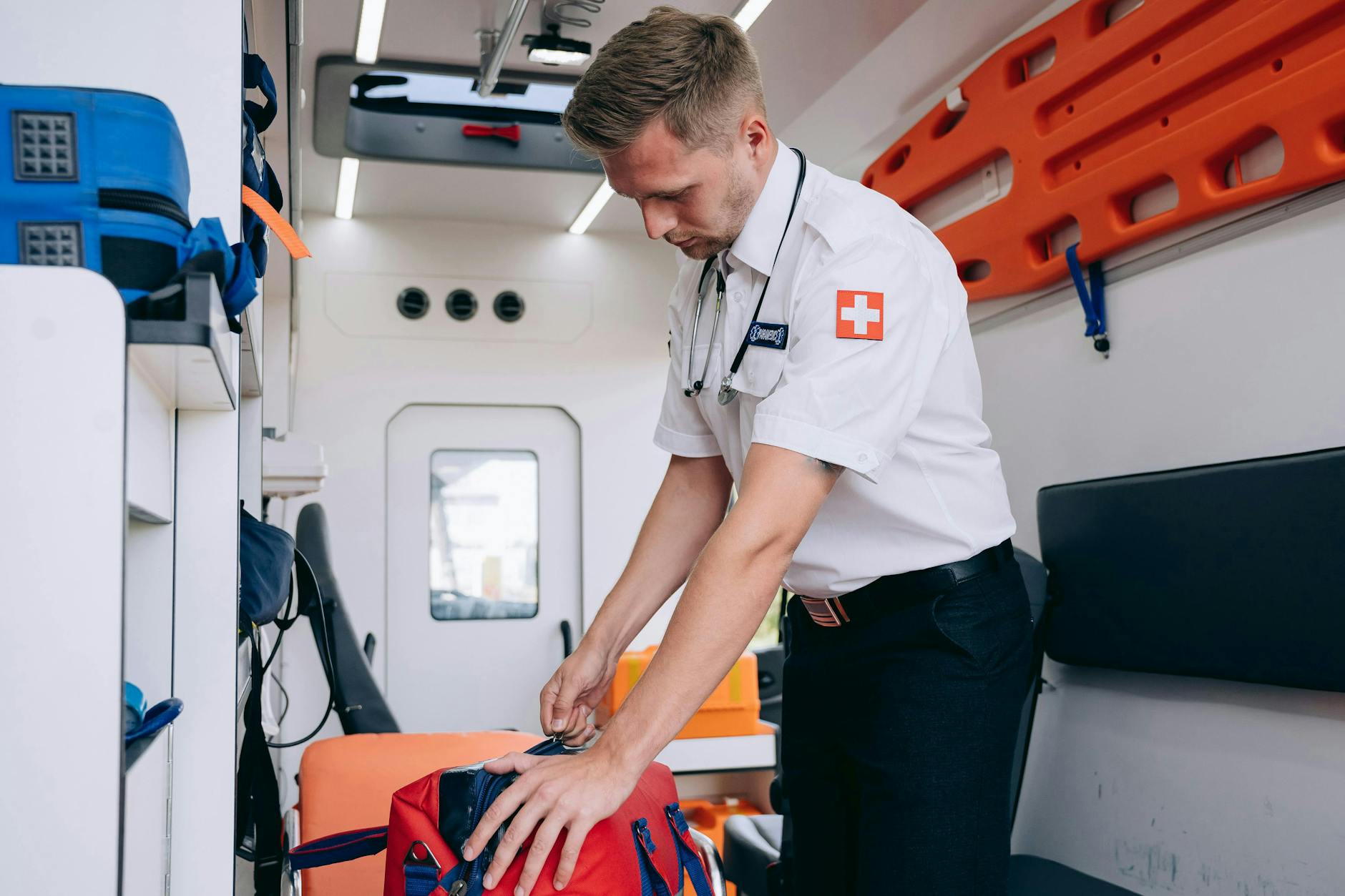 A paramedic in uniform organizes medical equipment inside an ambulance, preparing for emergency services — UPI Study