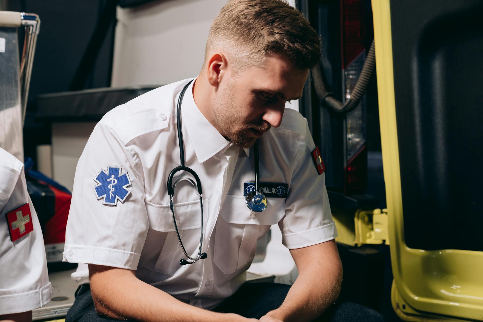 A paramedic in uniform sits pensively inside an ambulance, conveying healthcare dedication — UPI Study
