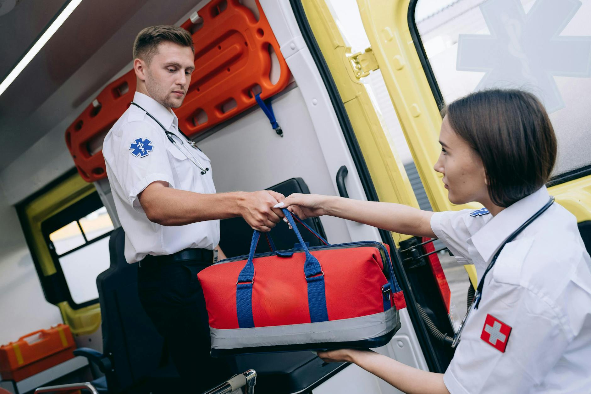 Male and female paramedics exchanging a medical kit inside an ambulance, showcasing teamwork — UPI Study