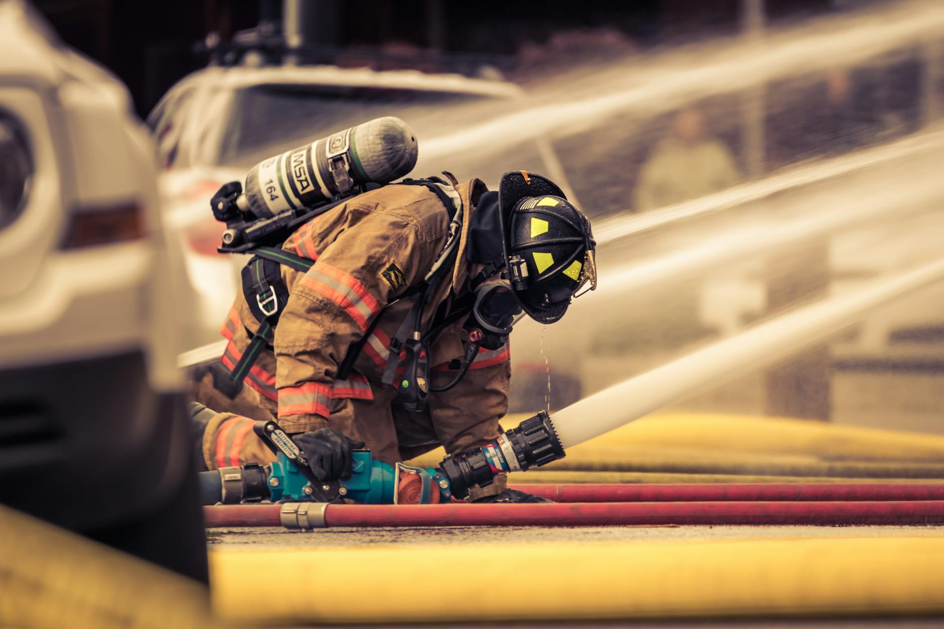 Firefighter in full gear handling water hose during emergency response training outdoors — UPI Study
