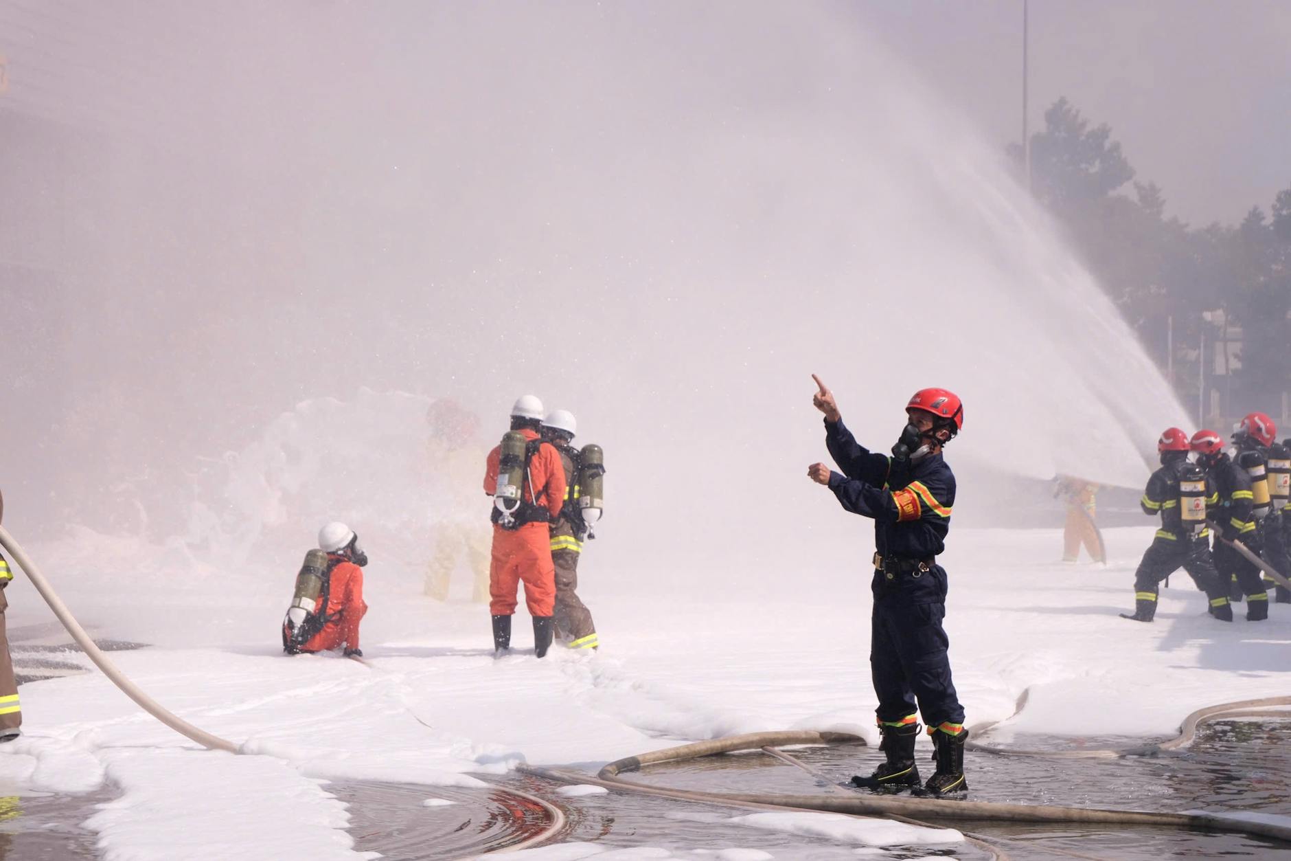 Firefighters in protective gear conduct a foam spraying training exercise outdoors — UPI Study