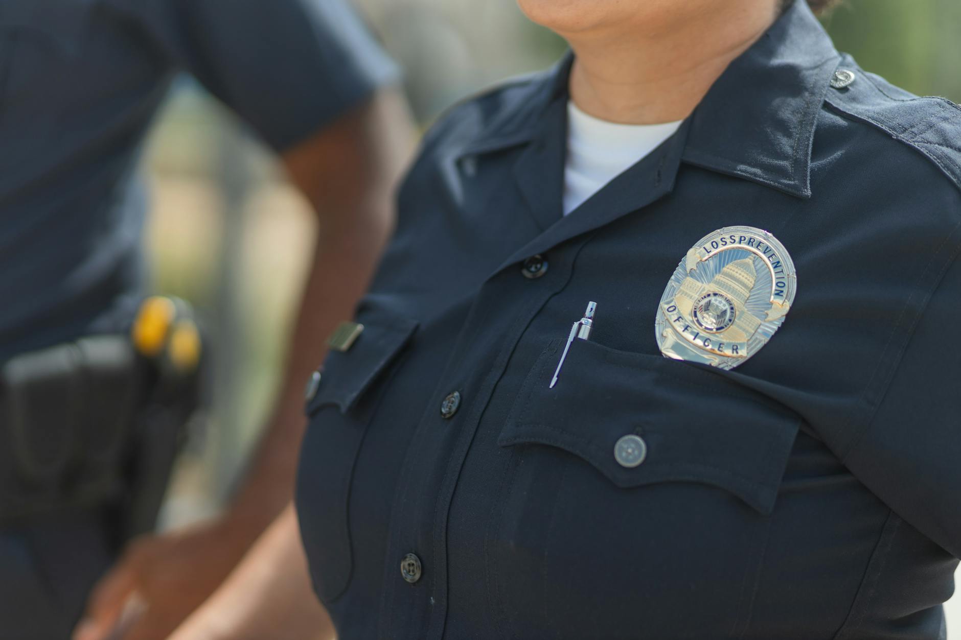 Close-up of police officers in uniform, displaying badge and radio outdoors — UPI Study