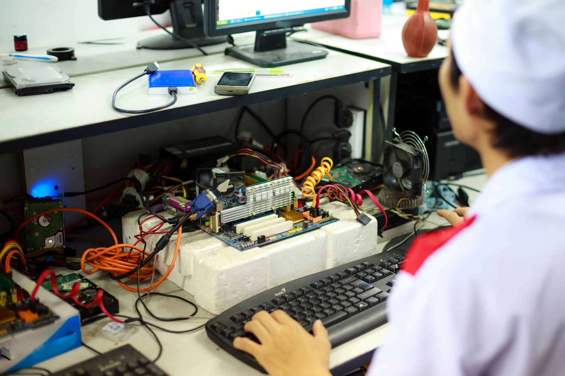 A man in a laboratory uniform working on computer components and wiring at a workstation — UPI Study