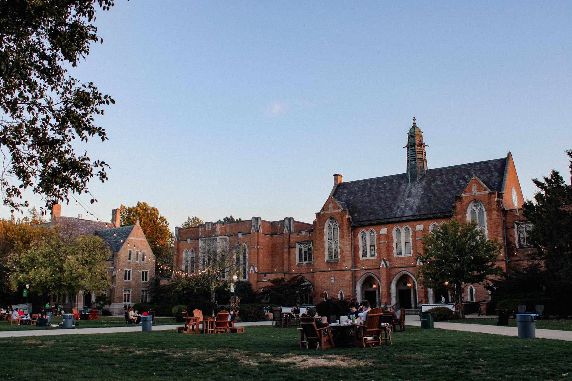 Scenic view of Notre Dame campus with Gothic-style buildings and students on a green field — UPI Study